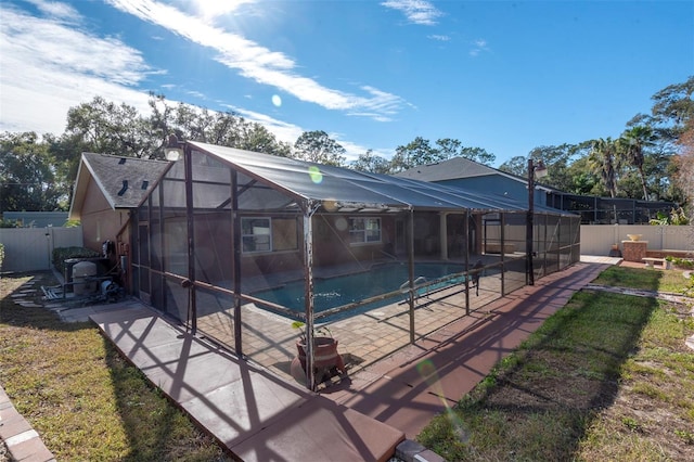 back of house featuring a lawn, glass enclosure, a fenced in pool, and a patio