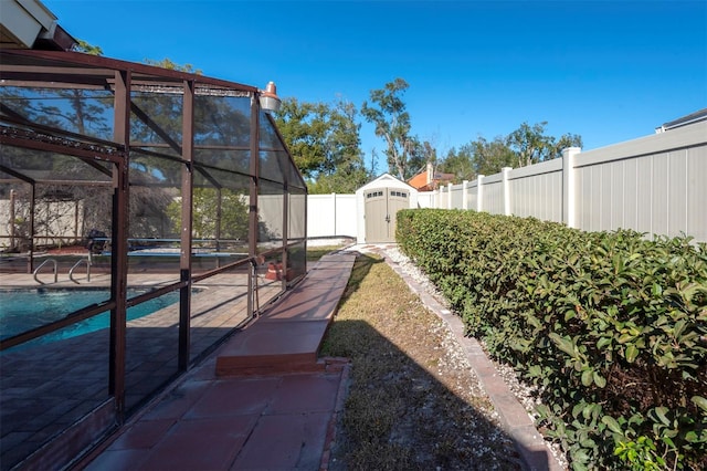 view of yard featuring a patio, a fenced in pool, a storage unit, and a lanai