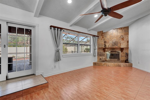 unfurnished living room with a textured ceiling, ceiling fan, tile patterned flooring, vaulted ceiling with beams, and a stone fireplace