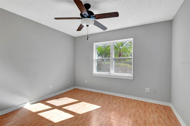 empty room with ceiling fan, light tile patterned flooring, and a textured ceiling