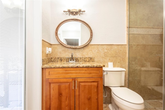 bathroom featuring vanity, toilet, tile walls, and a tile shower