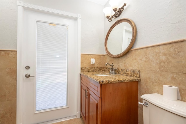 bathroom featuring vanity, toilet, and tile walls