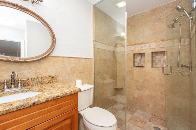 bathroom with an enclosed shower, vanity, toilet, and tile walls