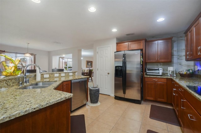 kitchen featuring light stone countertops, appliances with stainless steel finishes, tasteful backsplash, sink, and decorative light fixtures