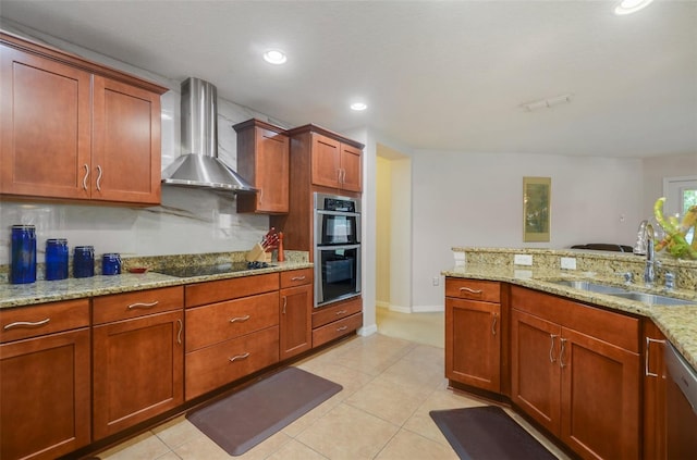 kitchen featuring sink, wall chimney exhaust hood, tasteful backsplash, light stone counters, and appliances with stainless steel finishes