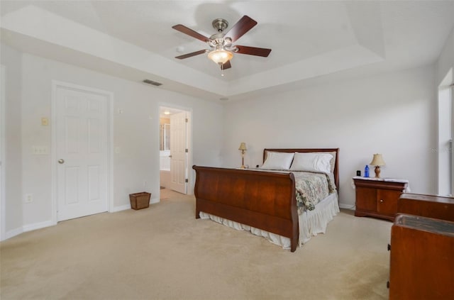 bedroom with a raised ceiling, ceiling fan, and light colored carpet