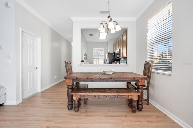 dining space featuring light hardwood / wood-style floors, an inviting chandelier, a wealth of natural light, and crown molding