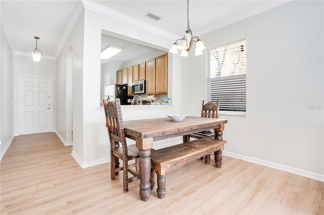 dining area featuring a chandelier, ornamental molding, and light hardwood / wood-style flooring