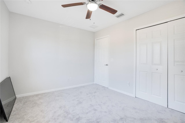 unfurnished bedroom featuring light carpet, a closet, and ceiling fan