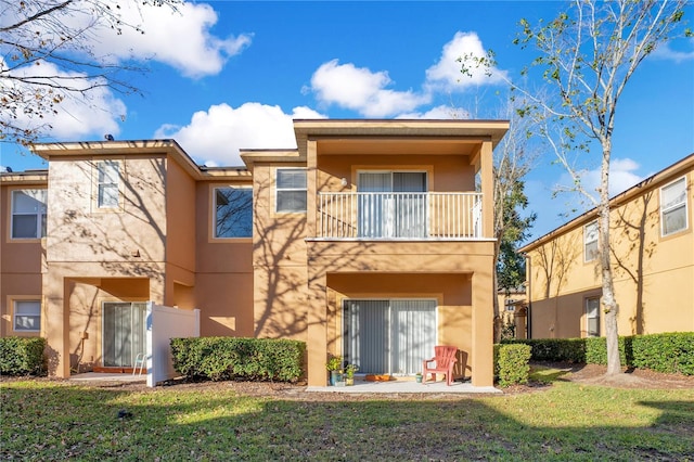 rear view of property with a lawn and a balcony