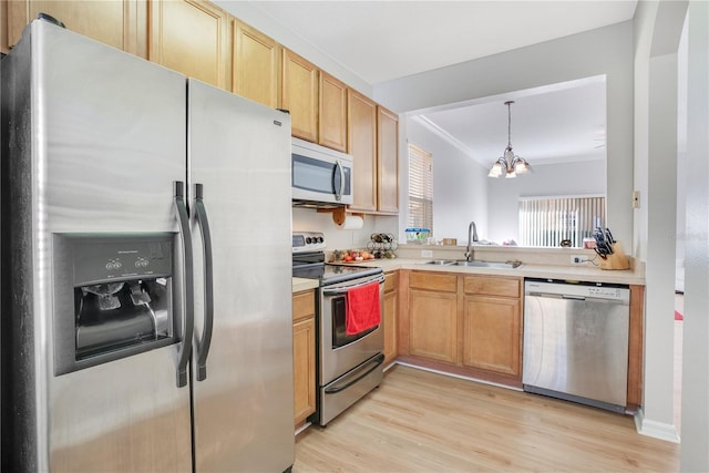 kitchen with appliances with stainless steel finishes, crown molding, sink, pendant lighting, and an inviting chandelier