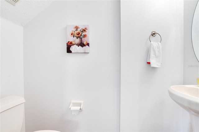 bathroom featuring sink, a textured ceiling, and toilet