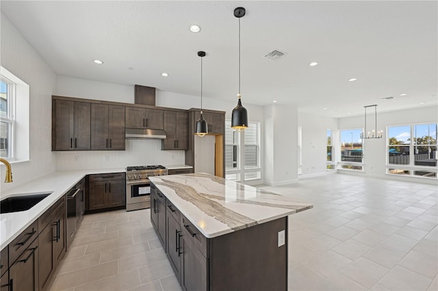 kitchen featuring decorative light fixtures, high end stove, sink, dark brown cabinetry, and light stone countertops