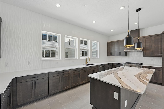 kitchen with stove, hanging light fixtures, a kitchen island, stainless steel dishwasher, and sink