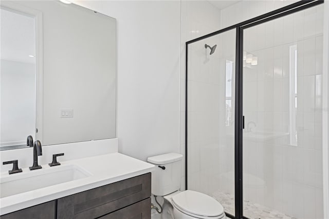 bathroom featuring toilet, a shower with shower door, and vanity