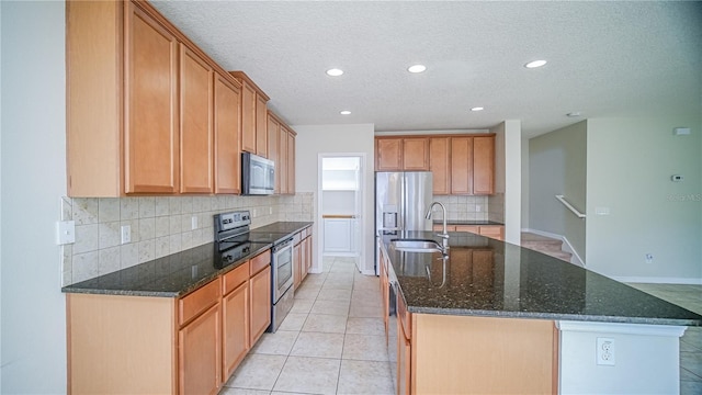 kitchen featuring light tile patterned flooring, sink, an island with sink, and appliances with stainless steel finishes