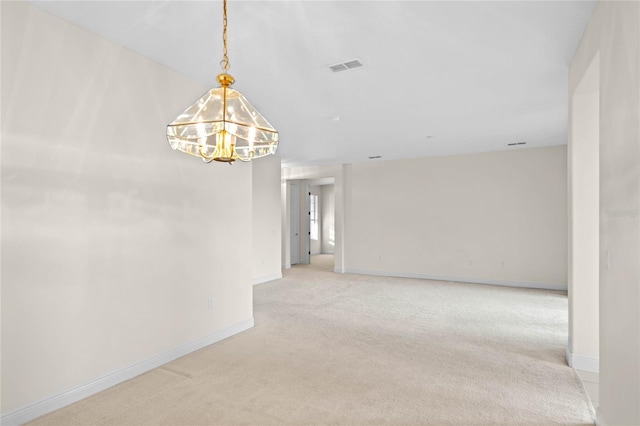 carpeted empty room with an inviting chandelier