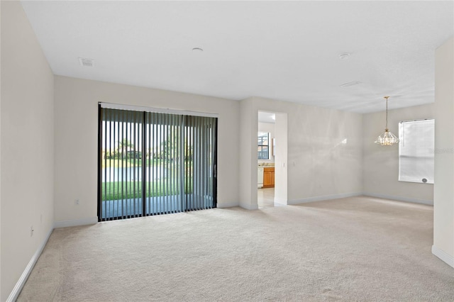 carpeted spare room featuring a chandelier