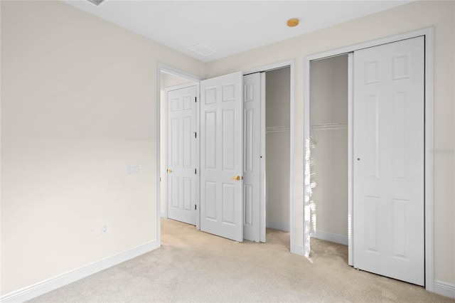 unfurnished bedroom featuring two closets and light carpet