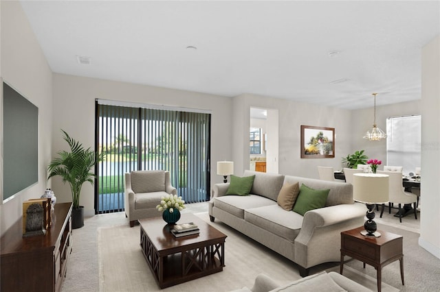 carpeted living room featuring a healthy amount of sunlight and a chandelier