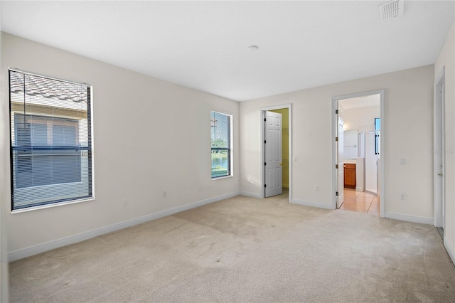 unfurnished bedroom with light colored carpet and connected bathroom