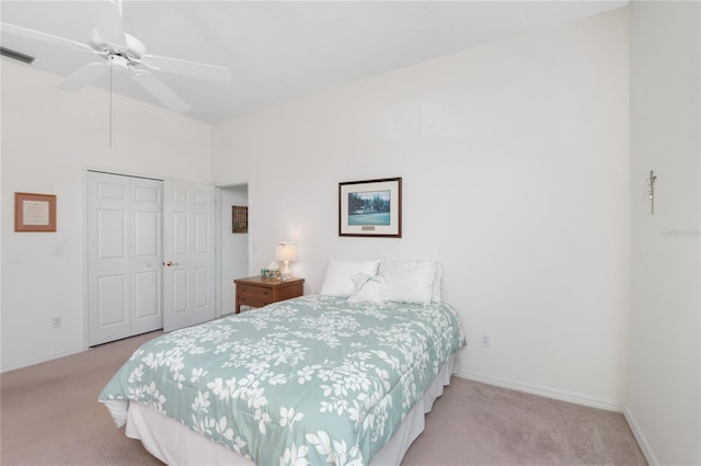 bedroom with ceiling fan, a closet, light carpet, and a high ceiling