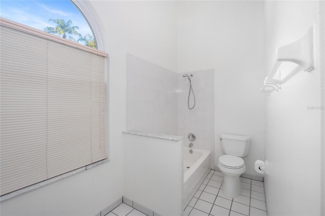 bathroom with tile patterned flooring, tiled shower / bath combo, and toilet