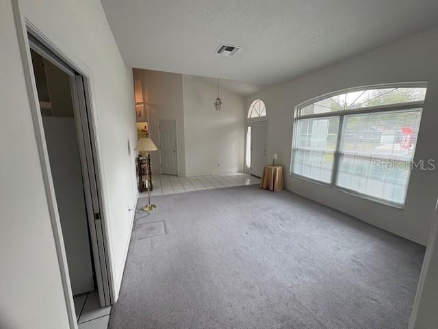 interior space featuring light carpet, a textured ceiling, and visible vents