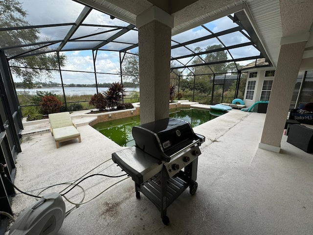 view of patio with glass enclosure, area for grilling, and a water view