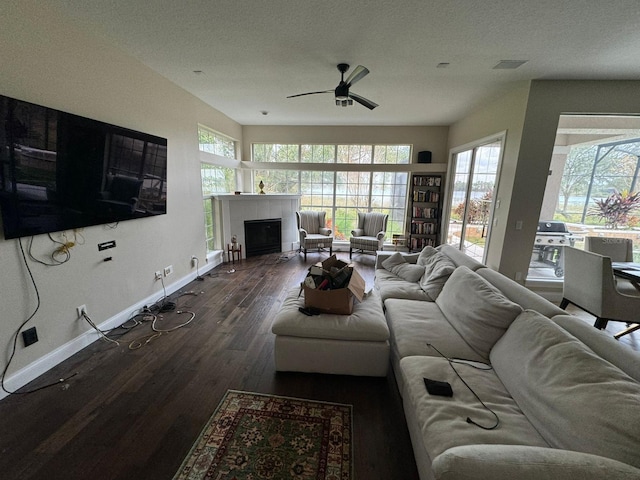 living room with a tiled fireplace, ceiling fan, dark hardwood / wood-style flooring, and a textured ceiling