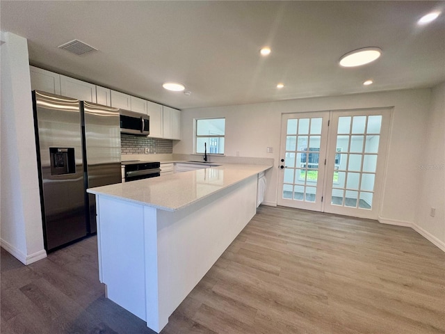 kitchen with sink, stainless steel appliances, kitchen peninsula, light hardwood / wood-style floors, and white cabinets