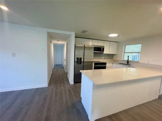 kitchen featuring white cabinetry, sink, stainless steel appliances, dark hardwood / wood-style flooring, and kitchen peninsula