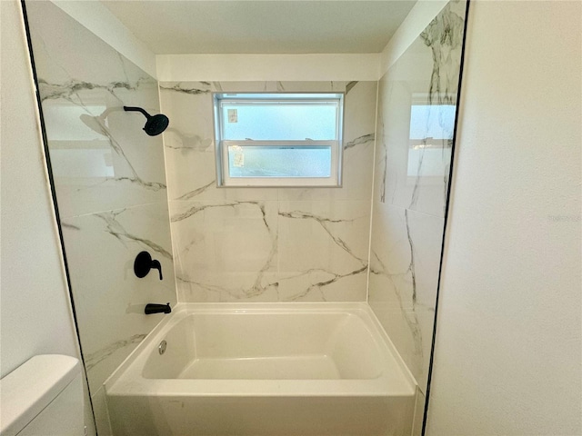 bathroom with tiled shower / bath combo and toilet