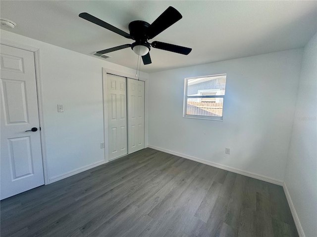 unfurnished bedroom with ceiling fan, a closet, and dark wood-type flooring