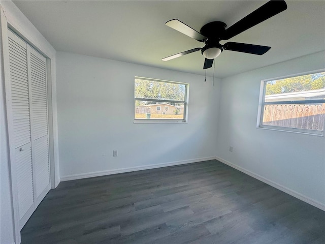 unfurnished bedroom with multiple windows, ceiling fan, a closet, and dark hardwood / wood-style floors