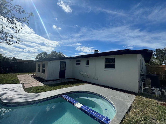 rear view of house featuring a swimming pool with hot tub and a patio