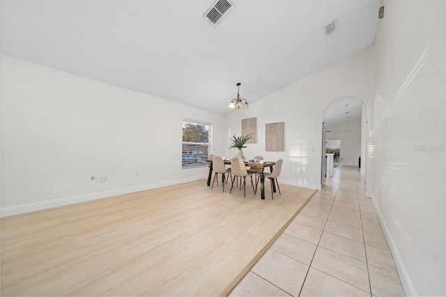 tiled dining space with vaulted ceiling and an inviting chandelier