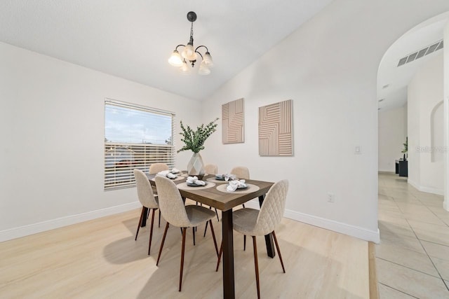 dining space featuring light tile patterned flooring, lofted ceiling, and a chandelier