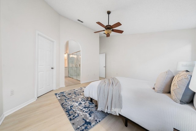 bedroom with ceiling fan, light wood-type flooring, ensuite bathroom, and lofted ceiling