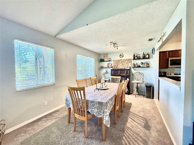 carpeted dining space featuring a textured ceiling, a wealth of natural light, and vaulted ceiling