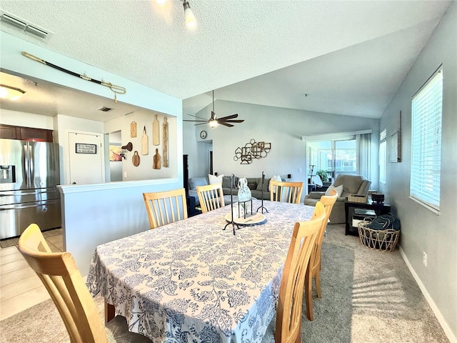 carpeted dining room with a textured ceiling, vaulted ceiling, and ceiling fan