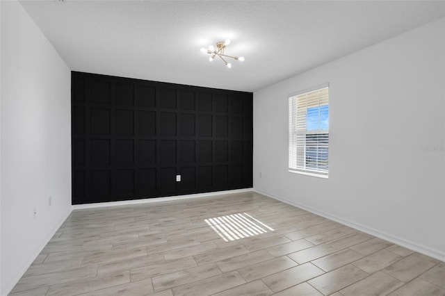 spare room featuring a textured ceiling and a chandelier