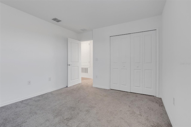 unfurnished bedroom with light carpet and a closet