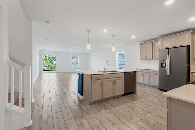 kitchen with sink, hanging light fixtures, a center island with sink, appliances with stainless steel finishes, and cream cabinets