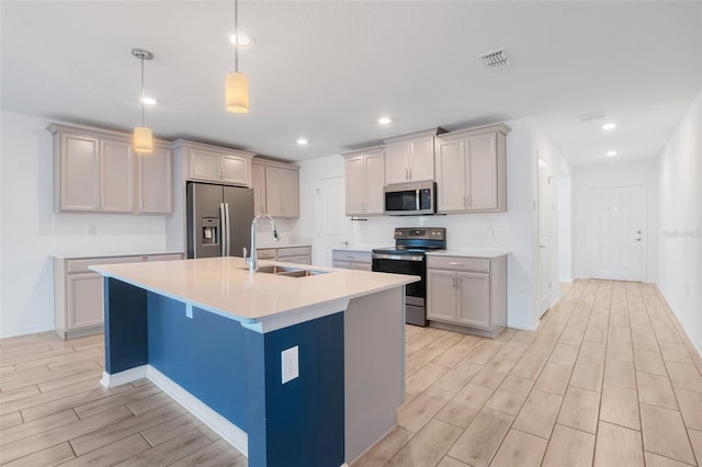 kitchen featuring sink, a breakfast bar, hanging light fixtures, stainless steel appliances, and a center island with sink