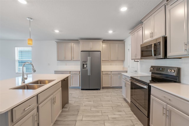 kitchen with gray cabinetry, sink, stainless steel appliances, and hanging light fixtures