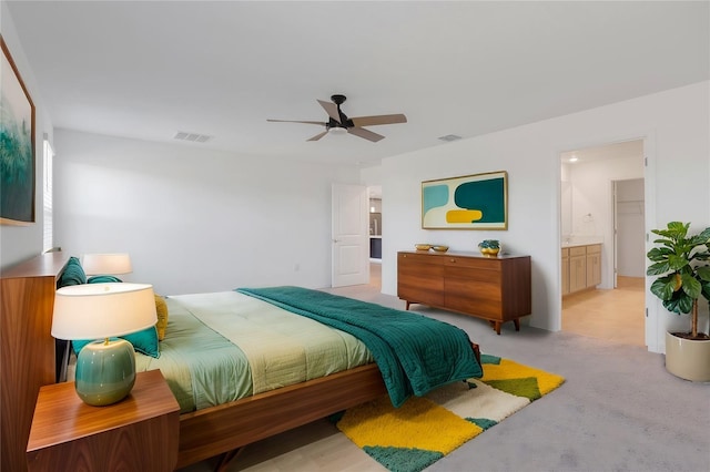 bedroom with light carpet, ceiling fan, and ensuite bathroom