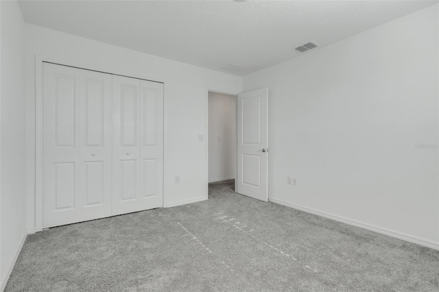 unfurnished bedroom with light colored carpet and a closet