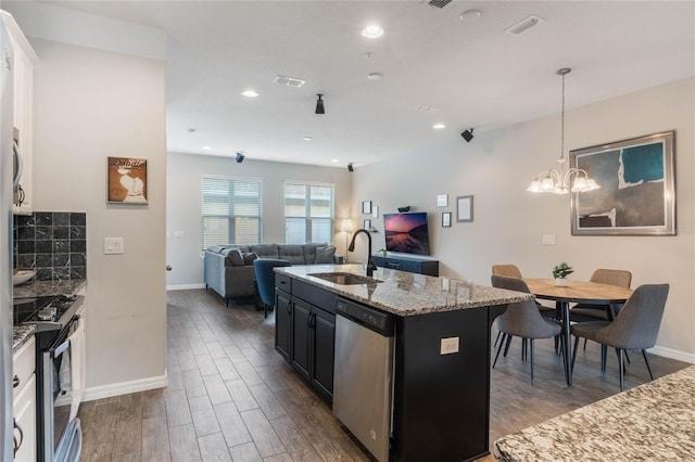 kitchen featuring light stone counters, stainless steel appliances, sink, a center island with sink, and hanging light fixtures