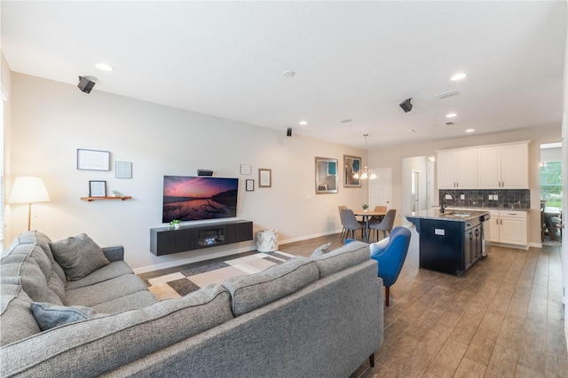 living room featuring a chandelier, sink, and wood-type flooring